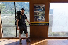 Jamie McHale standing in front of the Abel Tasman Coastal Track sign