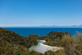 A view over a sandy inlet with the Tasman Bay in the background